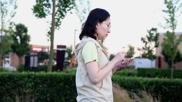 Mujer asiática caminando y leyendo información sobre el teléfono celular — Vídeo de stock