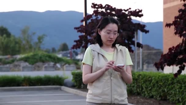 Mujer asiática caminando y leyendo información sobre el teléfono celular — Vídeo de stock