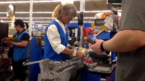 Människor som betalar livsmedel vid utcheckningen counter inne walmart butiken — Stockvideo