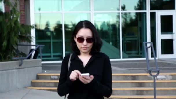 Mujer asiática que usa gafas de sol y lee el mensaje del teléfono móvil — Vídeo de stock