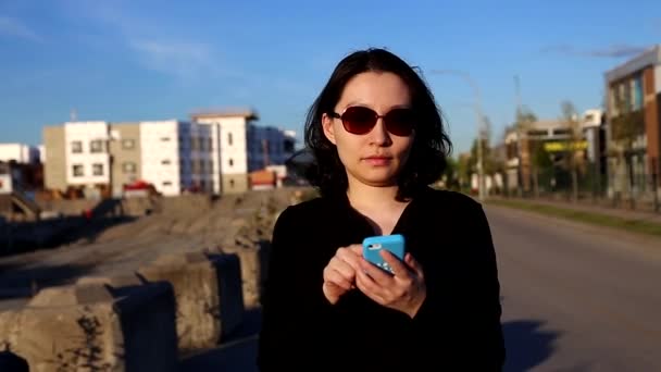 Aasialainen nainen kävely ja lukeminen uusi asunto tietoa matkapuhelin — kuvapankkivideo