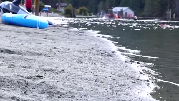 Un lado de la gente divirtiéndose en una orilla pacífica del lago — Vídeo de stock