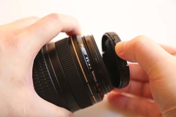 Mão tampa da lente em movimento sobre um fundo branco — Fotografia de Stock