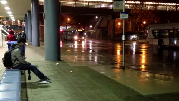 Lidé čekají autobusem na autobusovém nádraží Metrotown na prší den. — Stock video