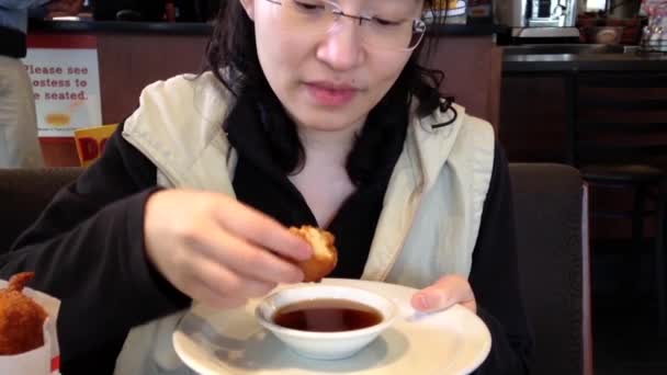 Cerca de la mujer comiendo cachorros panqueque con jarabe caliente — Vídeo de stock