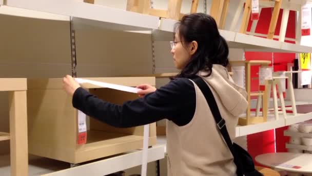 Mujer midiendo el tamaño de los muebles en la tienda Ikea — Vídeos de Stock