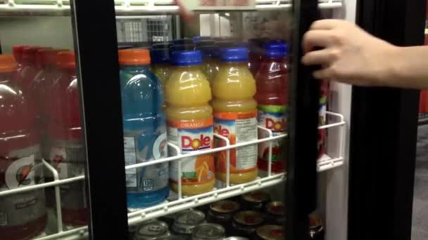 Woman taking juice from a cooler at convenience store. — Stock Video