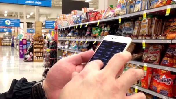 Man checking global exchange rate on iphone inside Save on foods. — Stock Video