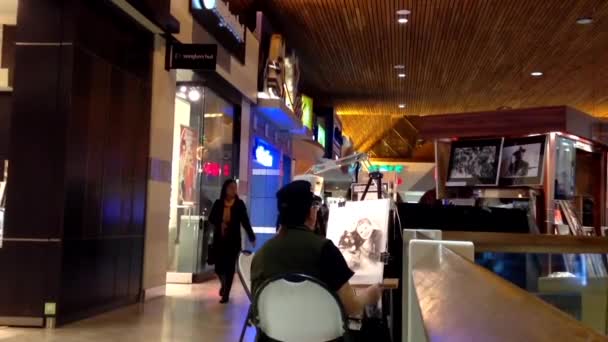 Man artist painting picture inside Coquitlam shopping mall during shopping season. — Stock Video