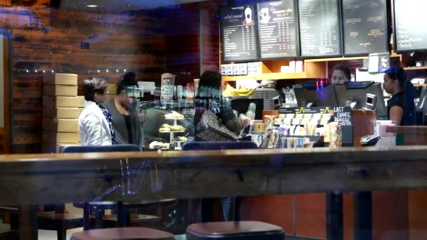 Filmado desde la ventana exterior del cliente comprando café en Starbucks — Vídeos de Stock