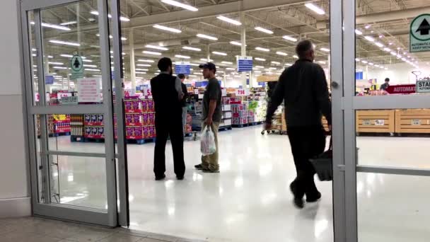 Personas con carrito de compras caminando a través de las puertas en la supertienda — Vídeo de stock