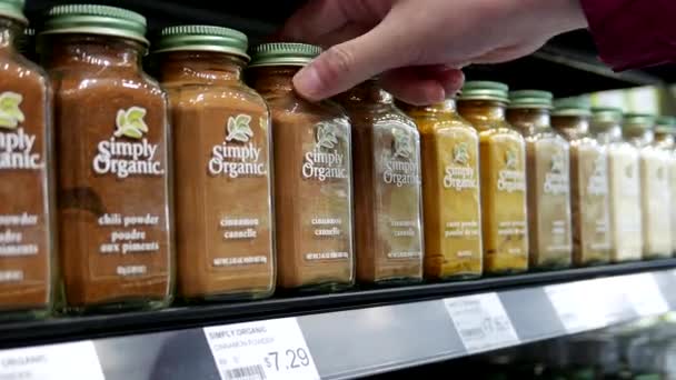 Mujer comprando canela y polvos de curry en estantes en supermercado orgánico — Vídeos de Stock