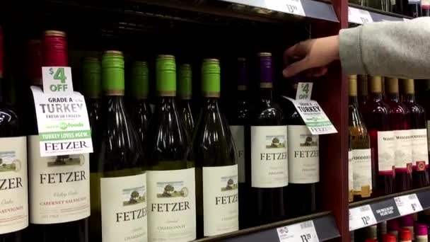 Une main prend des bouteilles de vin rouge de l'étagère — Video