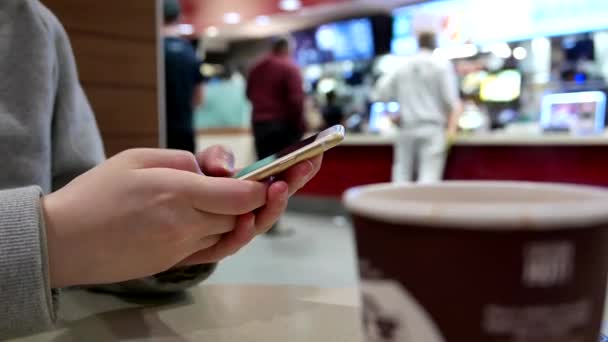 Mensaje de texto de la mujer en el teléfono móvil en el restaurante de comida rápida mcdonalds — Vídeo de stock