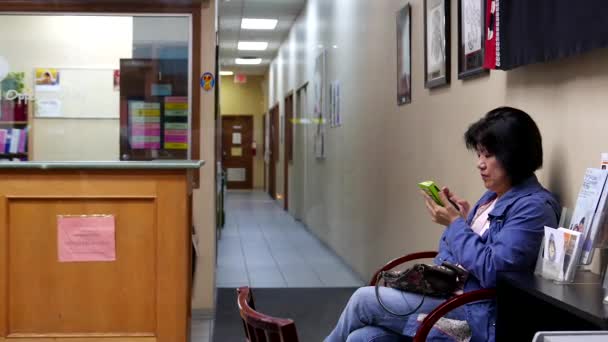 Mujer leyendo mensaje de teléfono móvil dentro del centro de aprendizaje para adultos CLOC — Vídeos de Stock