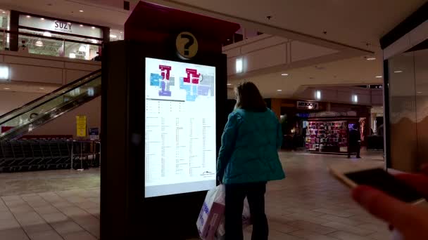 Woman checking store position in front of directory sign inside shopping mall — Stock Video