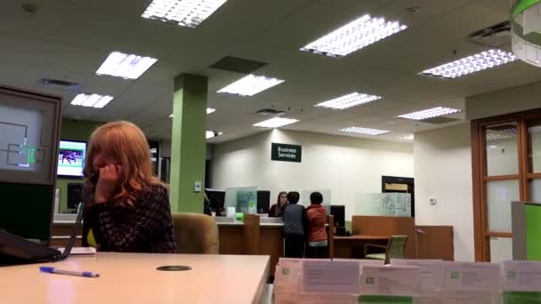 TD receptioniste antwoordende telefoongesprek met mensen praten aan de teller binnen Td Bank — Stockvideo