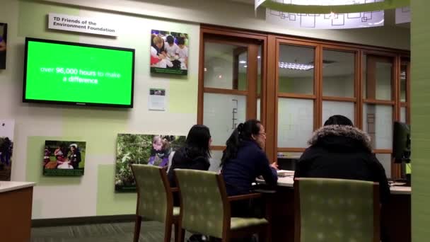 People at service counter talking to the bank receptionist inside TD Bank — Stock Video