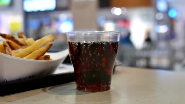 Una taza de cola de coca y papas fritas en la mesa en el patio de comidas dentro del centro comercial — Vídeo de stock