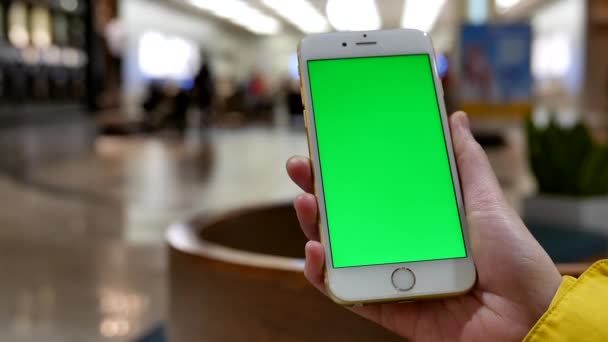 Жінка тримає пусті смарт-пристрій має зелений екран для користувача зміст перед apple store — стокове відео