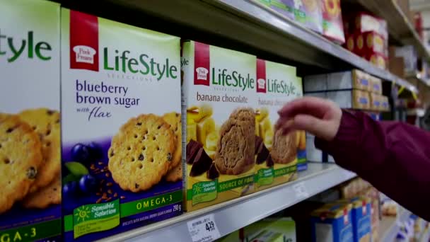 Woman selecting Lifestyle banana chocolate cookie in grocery store — Stock Video