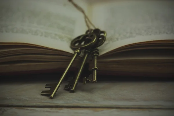 Antieke toetsen met de boek over houten achtergrond — Stockfoto