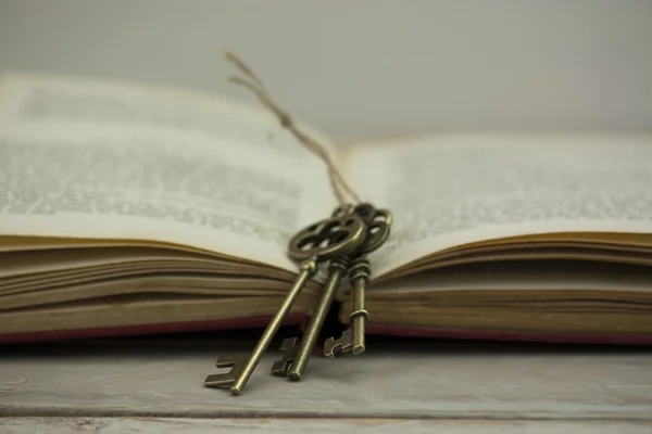 Antieke toetsen met de boek over houten achtergrond — Stockfoto