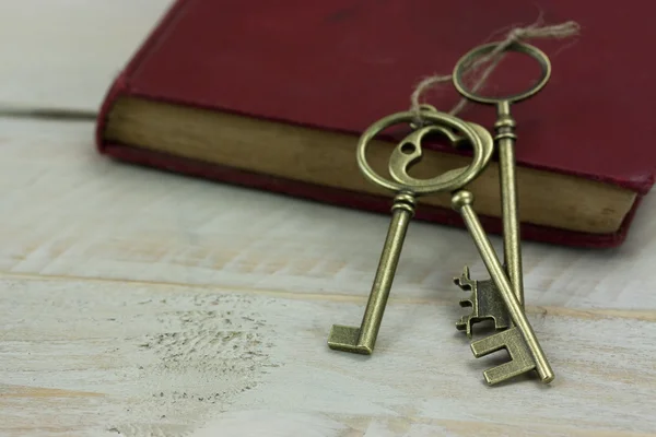 Old keys and book on a rustic background — Stock Photo, Image