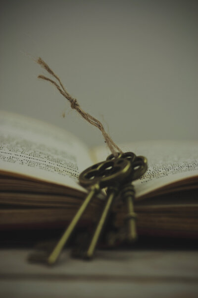 Antique keys with book on wooden background