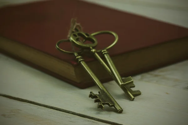 Vieilles clés et livre sur un fond rustique — Photo