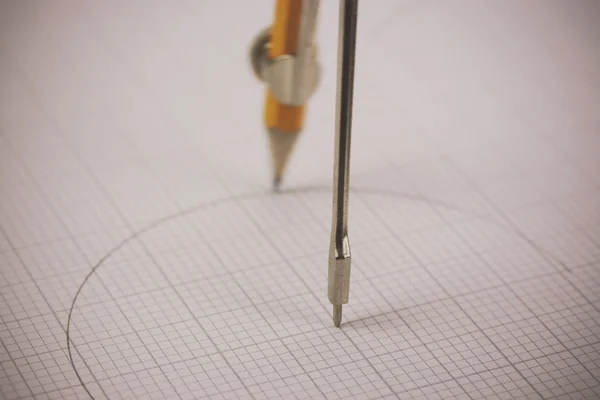 Närbild på en kompass på rutat papper — Stockfoto
