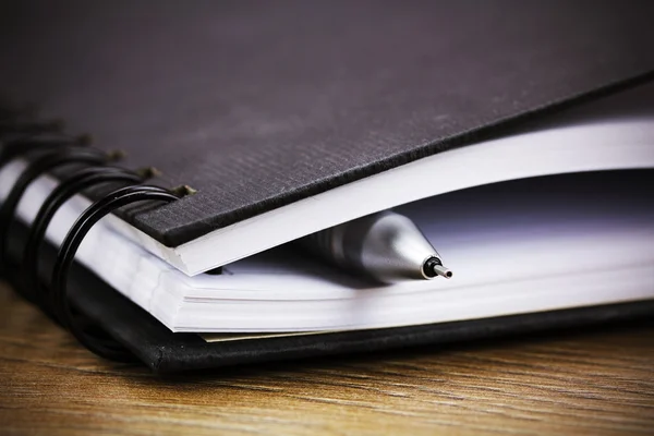 Cuaderno encuadernado en espiral negro sobre fondo de madera — Foto de Stock