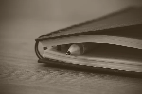 Cuaderno encuadernado en espiral negro sobre fondo de madera — Foto de Stock