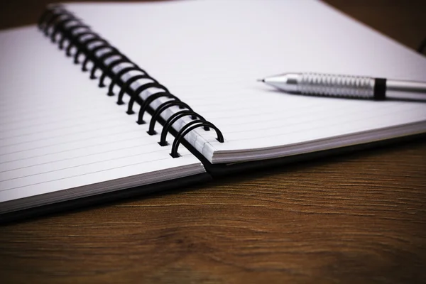 Black spiral bound notebook on wooden background — Stock Photo, Image