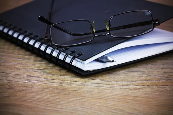 Cuaderno encuadernado en espiral negro sobre fondo de madera — Foto de Stock