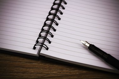 Ahşap arka plan üzerinde siyah sarmal ilişkili not defteri