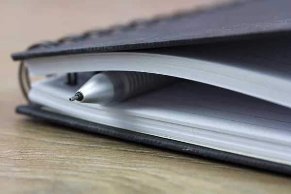 Cuaderno encuadernado en espiral negro sobre fondo de madera — Foto de Stock