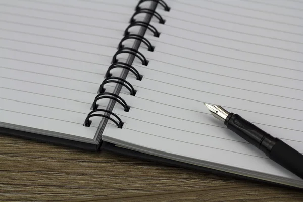 Black spiral bound notebook on wooden background — Stock Photo, Image