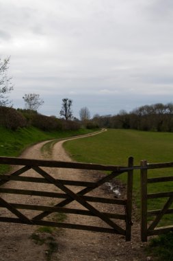 Wooden gate across a path in the countryside clipart
