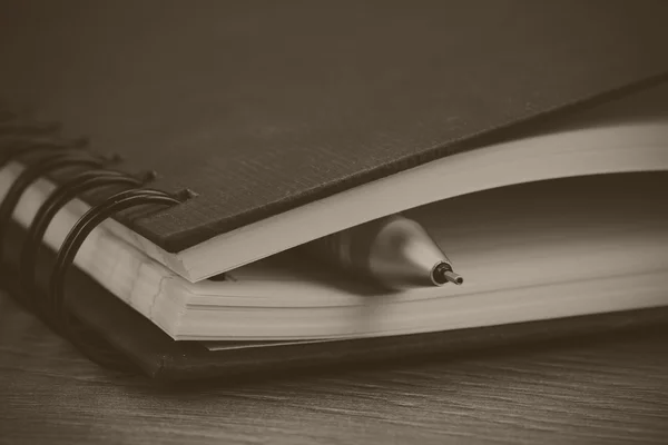 Black spiral bound notebook on wooden background — Stock Photo, Image