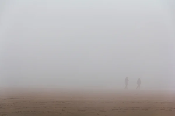 Ludzi, spacery wzdłuż plaży mist objęte — Zdjęcie stockowe