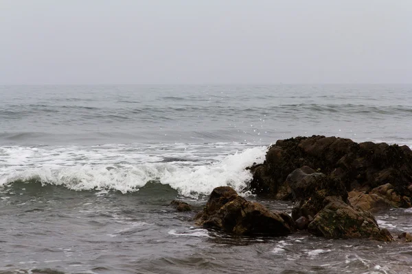 Vlny nad skály na pláži — Stock fotografie