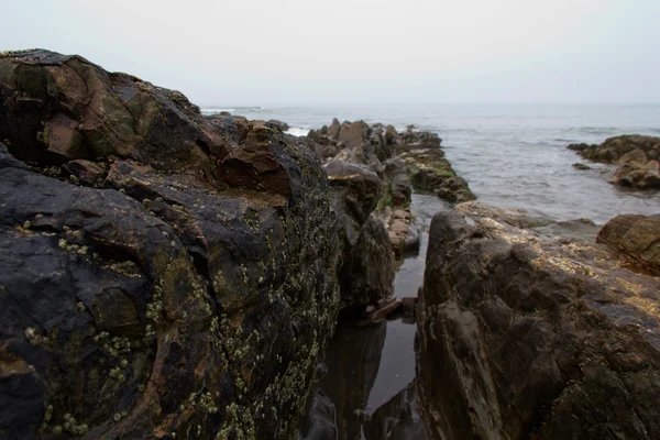 Vågorna över stenarna på stranden — Stockfoto