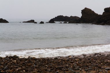 Dalgalar sahildeki kayaların üzerinde