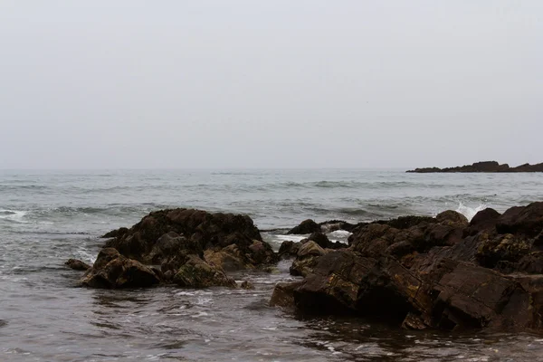 Хвилі над скелями на пляжі — стокове фото