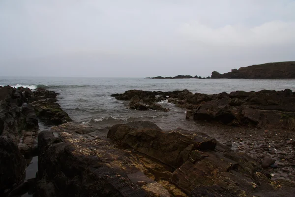 Wellen über die Felsen am Strand — Stockfoto