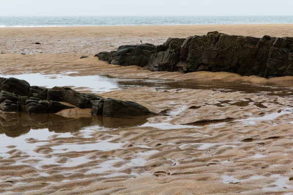 Arena húmeda y rocas en la playa — Foto de Stock