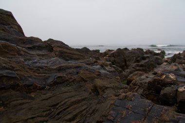 Dalgalar sahildeki kayaların üzerinde