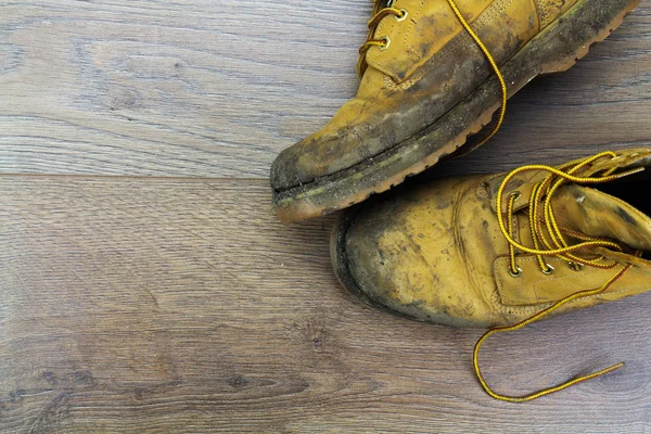 Muddy work boots on a wooden floor Royalty Free Stock Images