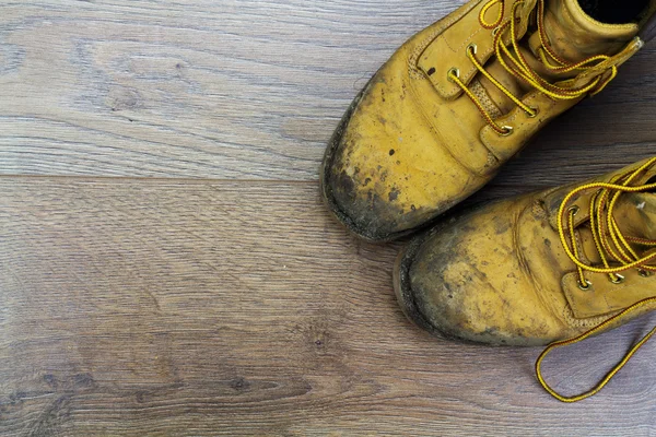 Muddy work boots on a wooden floor Stock Image